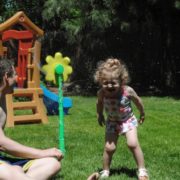 Father and daughter playing in sprinkler