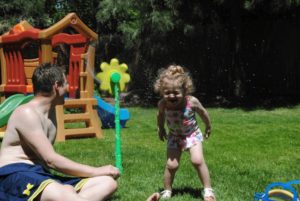 Father and daughter playing in sprinkler