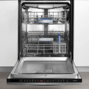 A modern dishwasher with an open door, showing neatly arranged dishes, glasses, and utensils inside, ready for cleaning.