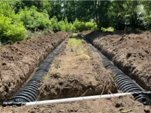 Trenches dug for drainage with corrugated pipes in a garden area.