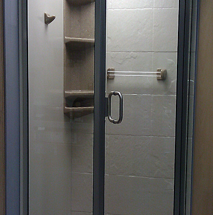 A modern glass shower enclosure with a metal frame and wall-mounted fixtures.