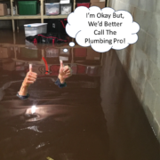 A man standing ankle-deep in water in a flooded basement, looking concerned as he assesses the damage. Boxes and furniture are partially submerged, highlighting the severity of the flooding.