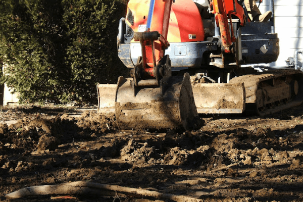 Image of plumbers digging in the front lawn to repair a sewer line, indicating extensive plumbing work