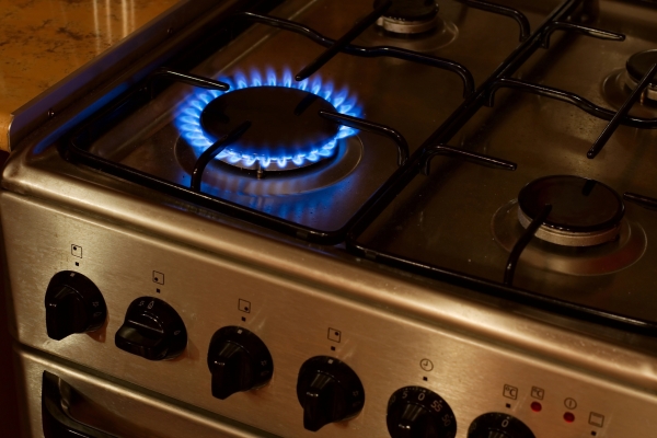 Gas stove with burner lit, emitting a warm flame for cooking dinner