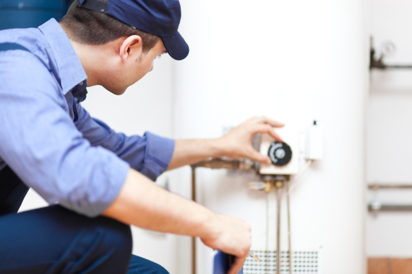 Plumber inspecting a water heater, ensuring proper functioning and maintenance